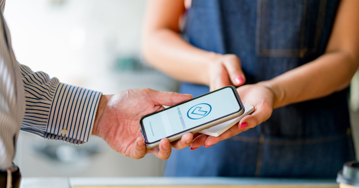 A woman hands a phone to a man to discuss the cost of building a house in Austin.