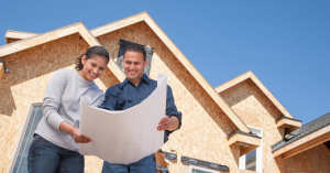 A man and woman examining house blueprints to determine the cost of construction in Austin.