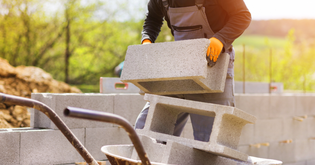 A construction worker building a house in Houston and stacking concrete blocks on a wheelbarrow.