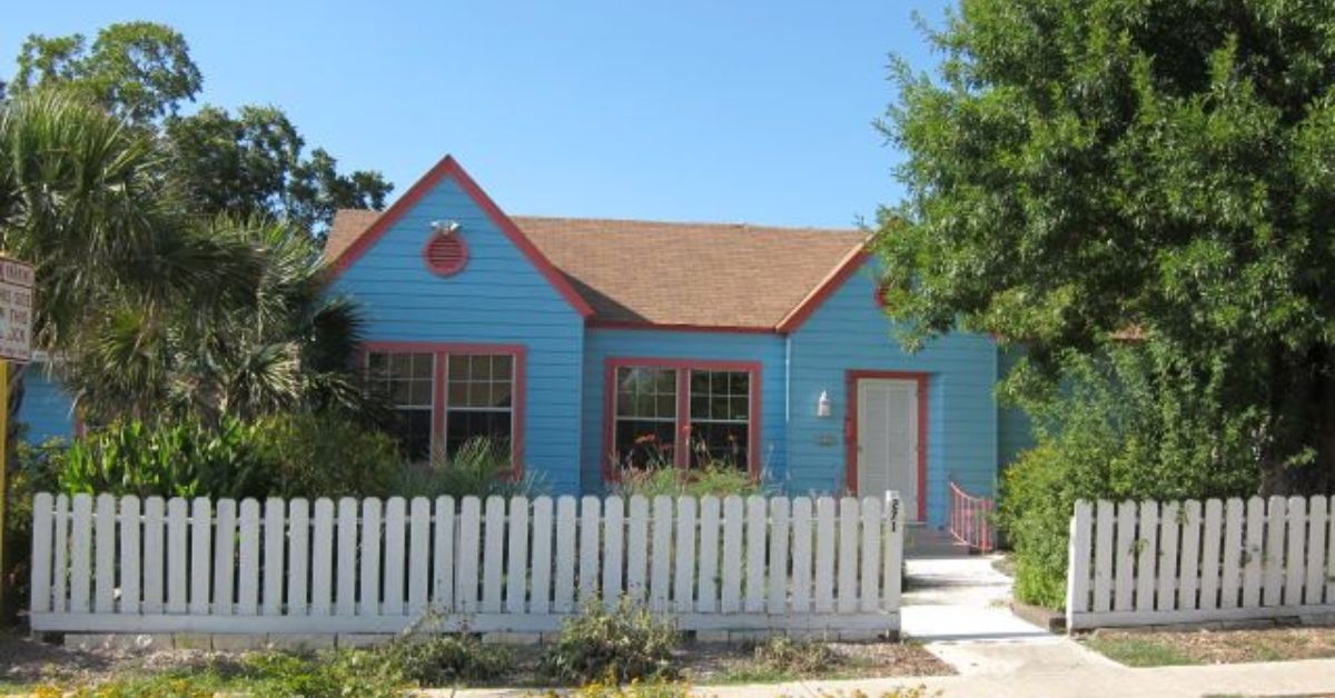 A blue house with a white picket fence located in Mahncke Park, one of the best neighborhoods to live in San Antonio.