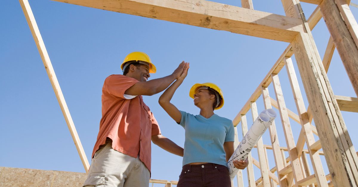 A couple standing under a wooden frame ready to build a house in Austin.