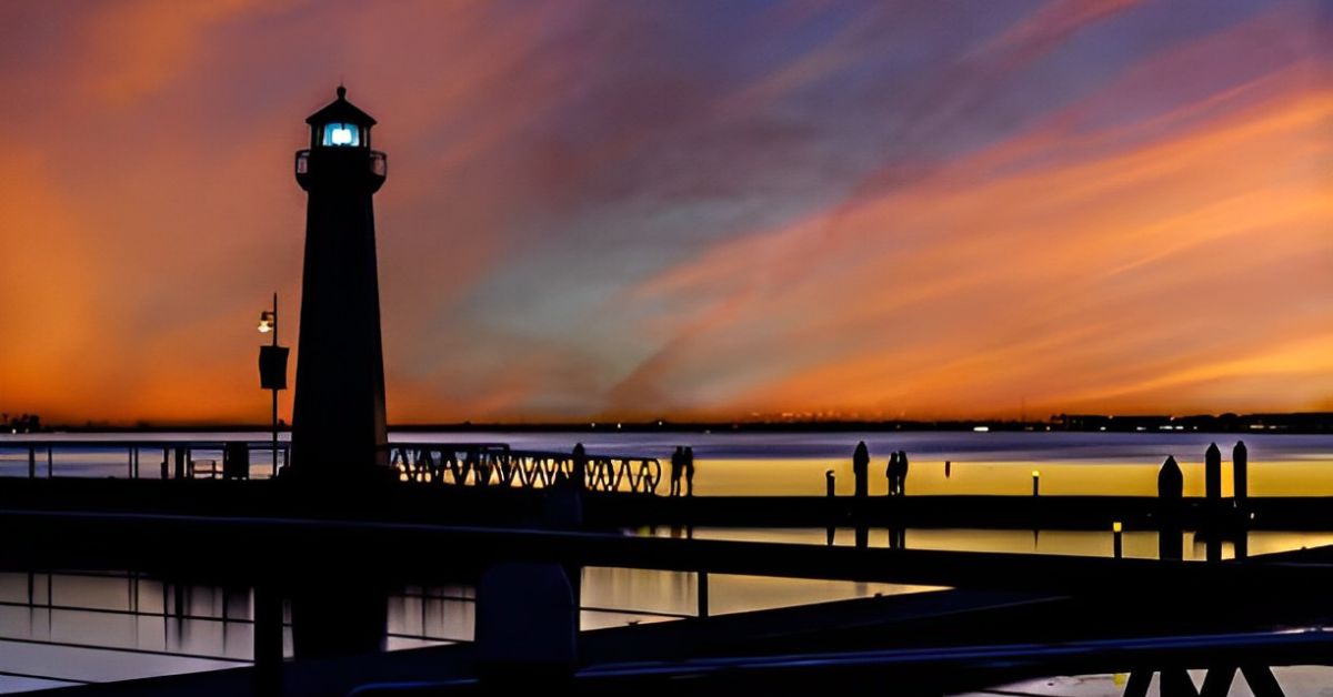 A lighthouse in one of the best suburbs to retire in Dallas TX, situated on a dock overlooking a rockwall harbor at sunset.