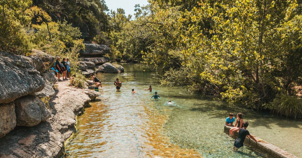 A group of people are swimming in a river in Wimberley, Austin TX.